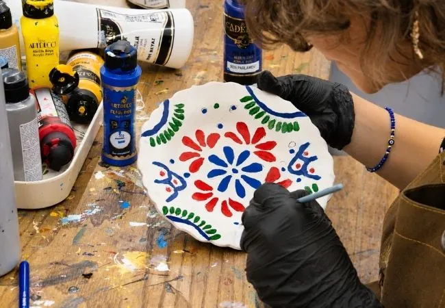 Woman painting a traditional Turkish ceramic plate with floral patterns