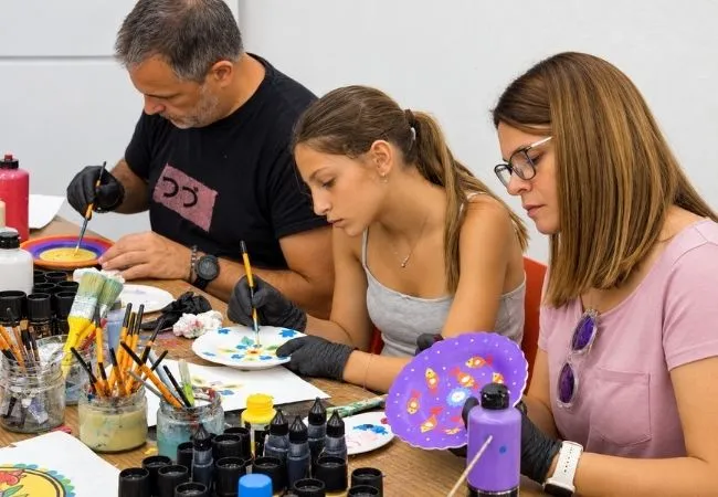 Family taking part in a ceramic plate painting workshop
