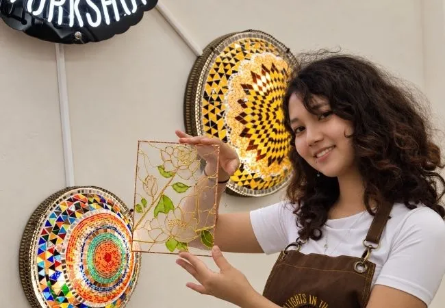 Participant displaying a handmade floral stained glass painting