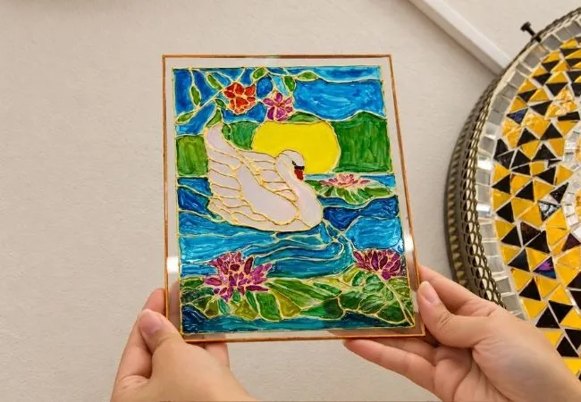 Hand-painted stained glass artwork with a colorful swan design