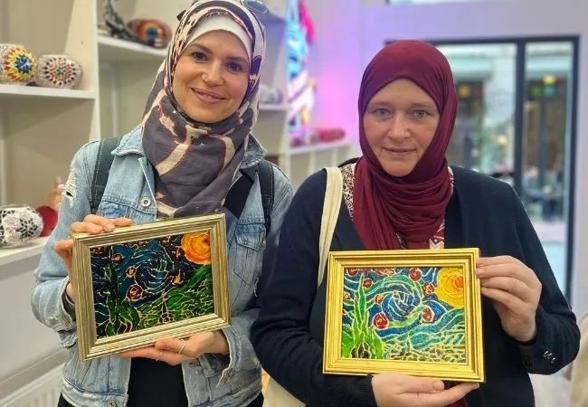 Participants holding their finished stained glass paintings after a workshop in Istanbul