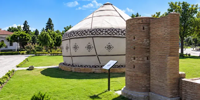 Traditional yurt and historic brick structure in a landscaped cultural park