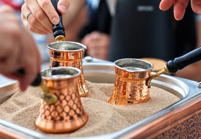 Traditional Turkish coffee pots used for coffee brewing on hot sand